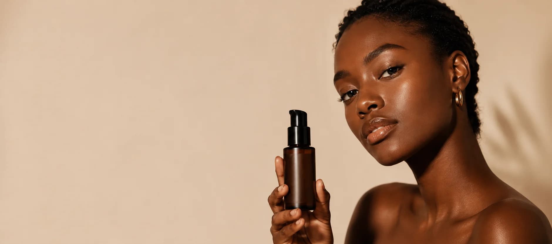 Woman with melanin-rich skin holding a bottle of serum